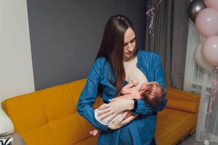 Young woman breastfeeding her baby in bedroom.