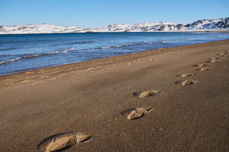 Wide shot of the beach at sunset, during the Winter with snow still on the sand.
