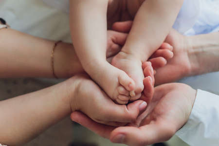 Mother uses her hand to hold her babys tiny hand to make him feeling her love, warm and secure.の写真素材