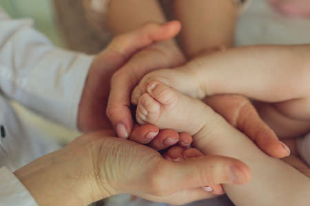 Mother uses her hand to hold her babys tiny hand to make him feeling her love, warm and secure.の写真素材