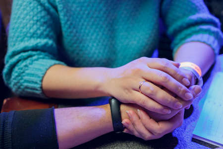 Close up male and female holding hands over table.の写真素材