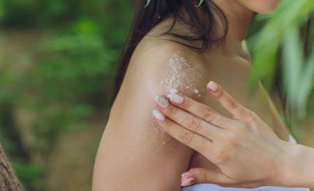 A woman gives suntan cream to another woman on her body while shes lying down.