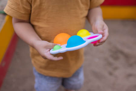 colorful trendy antistress sensory toy fidget push  and simple dimple in kids hands, children share toys and playing together.の写真素材