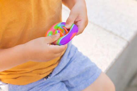 Colorful antistress sensory toy fidget it in toddlers hands. Antistress trendy toy. Rainbow sensory fidget. New trendy silicone toy. Snappersの写真素材