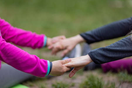 Group stretching workout - three cute girls stretches outdoors on a green grass field in park