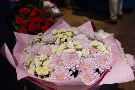 Colorful bouquet of different fresh flowers against brick wall. Bunch of orchids, roses, freesia and...