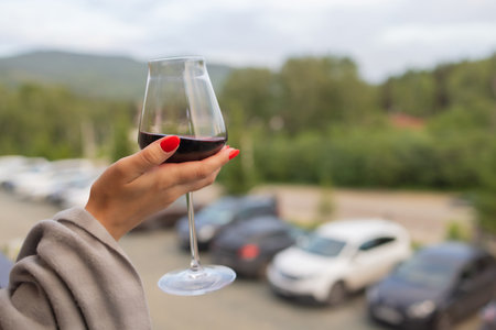 Male hand holding glass with wine on blurred natural background.の写真素材
