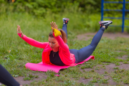 Happy young woman doing some stretching exercises at the park.