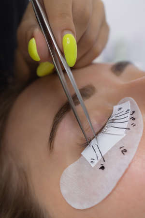 Beautiful Woman with long eyelashes in a beauty salon. Eyelash extension procedure. Lashes close up.の写真素材