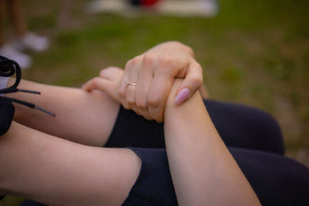 Group stretching workout - three cute girls stretches outdoors on a green grass field in park.