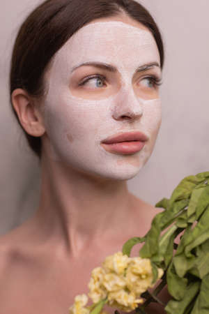 Spa Woman applying Facial clay Mask. Beauty Treatments. Close-up portrait of beautiful girl with a...