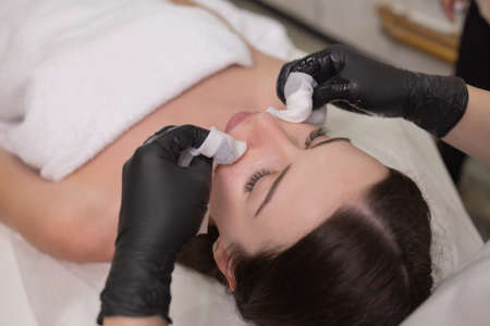 Facial skin care and protection. A young woman at a beauticians appointment. The specialist applies a cream mask to the face.の写真素材
