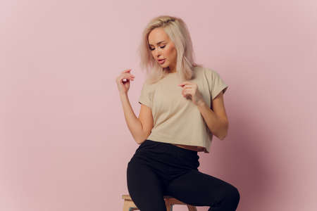 young pretty blonde woman laughing happily with arms crossed, with a relaxed, positive and satisfied pose against pink flat wall.の写真素材