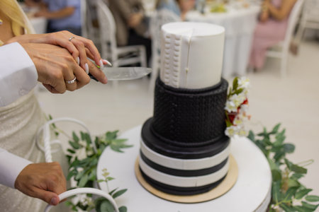 hands of bride and groom cut of a slice of a wedding cake.の写真素材