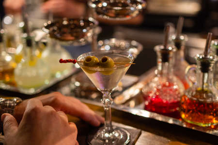 martini with green olives on a table in bar.の写真素材