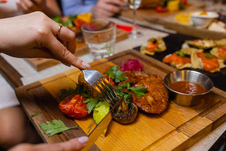 Young woman eating grilled steak in restaurant.の写真素材