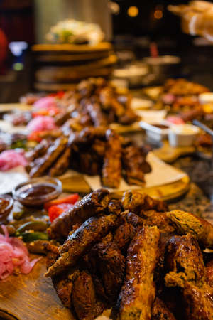 Assorted meat on a plate close up. Different types of meat and potatoes in a heap. Appetizer on a...