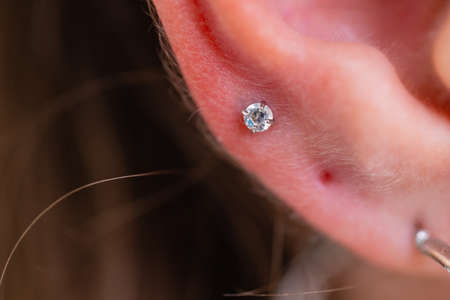 Professional holding the jewel of piercing just before screw the ball.