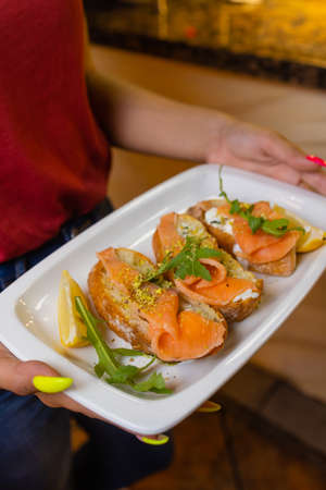 Woman waiter holding a wooden tray with bruschetta in her hand.の写真素材