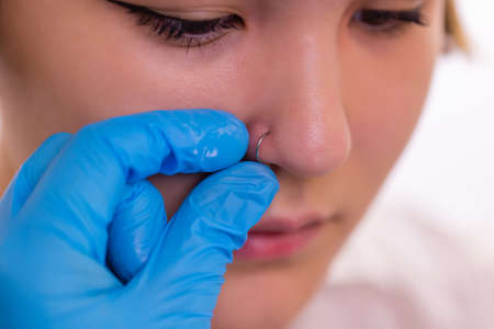 Closeup of a young womans visage with piercing hanging from her nose.の写真素材