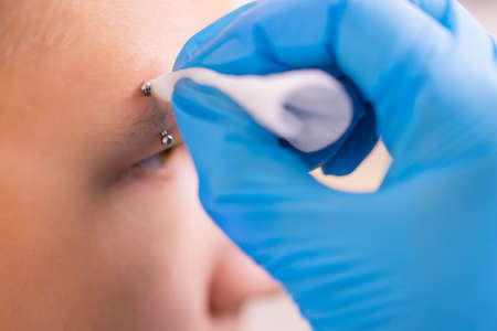 Man with pierced eyebrow. Three small black piercings.の写真素材