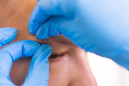 Man with pierced eyebrow. Three small black piercings.