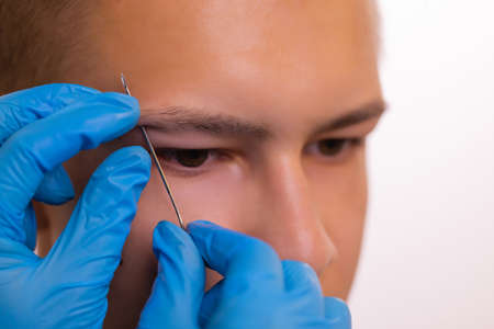 Man with pierced eyebrow. Three small black piercings.