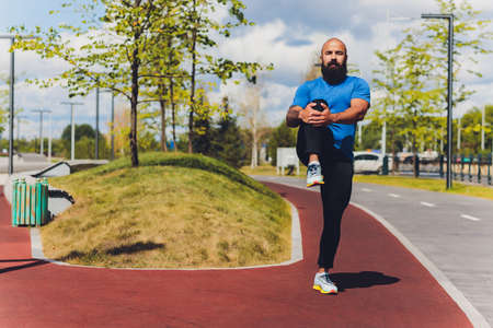Young athlete running fast outdoors. Wearing sport cloth, doing wide step, demonstrating healthy way of life, wide shot.の写真素材