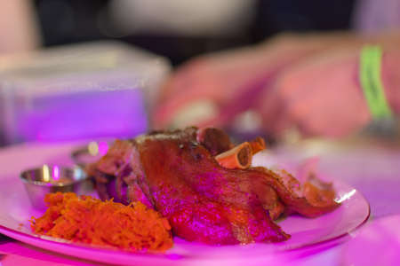 Unusual plate with pork knuckle. Unusual wooden plate with delicious pork knuckle and side dishes upon.の写真素材