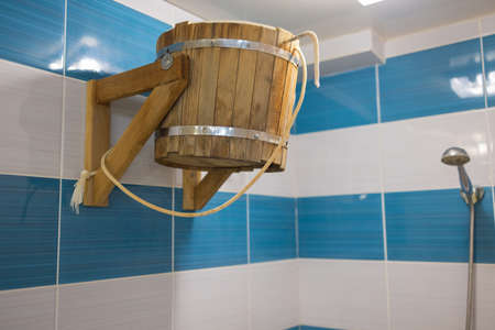 Wooden tipping bucket hangs on stone wall in sauna.の写真素材