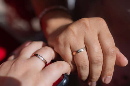 The bride and groom show hands and fingers with wedding gold rings close-up. Photography, concept.の写真素材