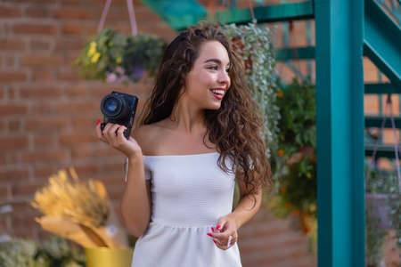 Young attractive female student or tourist using a mirrorless camera while walking in summer city. Woman takes pictures and enjoy weather.の写真素材