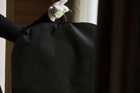 Black garment, suit travel bag. the hands of a hotel worker in white gloves.の写真素材