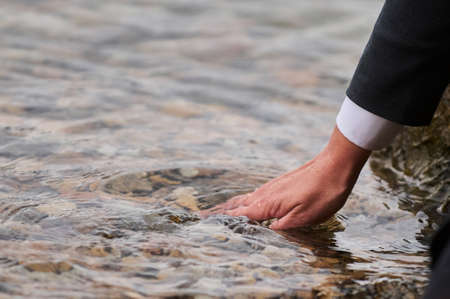 Womans hand on the mattress touch water.