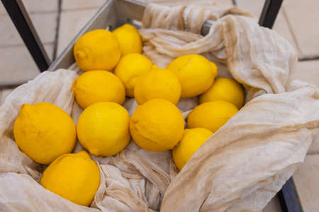 Yellow lemons in the bag - mesh on white linen tablecloth.の写真素材