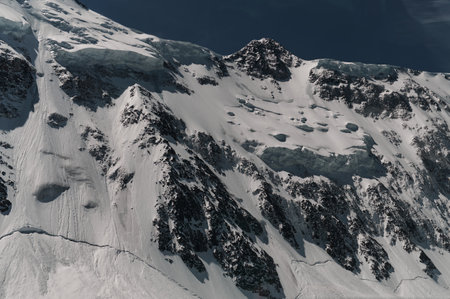 Minimalist view of snow-capped mountain wall in thick low clouds in sunshine. Scenic bright mountain...