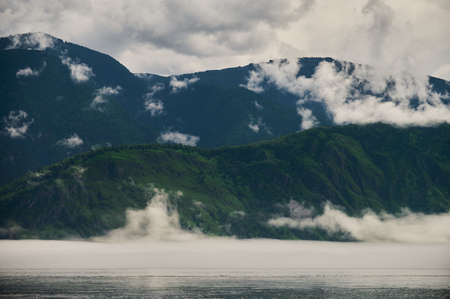 Fog in the mountain valley. Morning fog over the lake in the Altai mountains.の写真素材