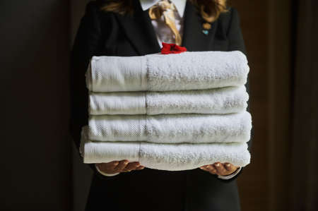 female hand holding stack clean bath towels colorful cotton terry textile background closeup.の写真素材