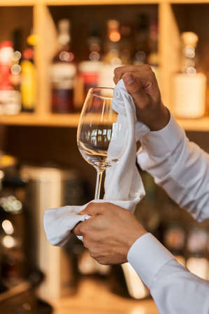 Waiter serving the table.Closeup of empty glass for wine, plate on the white tablecloth against break wall.の写真素材