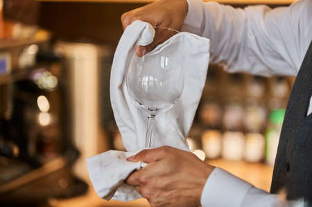 Waiter serving the table.Closeup of empty glass for wine, plate on the white tablecloth against break wall.の写真素材