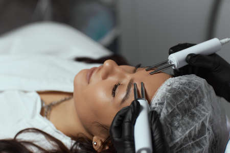 Cosmetology. Beautiful Woman At Spa Clinic Receiving Stimulating Electric Facial Treatment From...