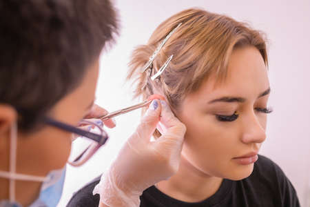 Professional placing the jewel of piercing on the ear with ball. Tragus type.の写真素材