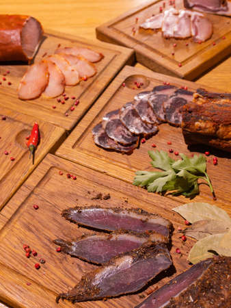 Sliced smoked gammon on a wooden table with addition of fresh herbs and aromatic spices.の写真素材