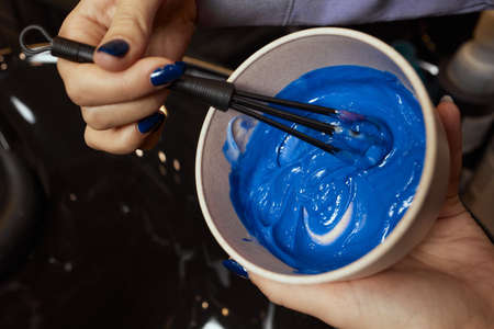 girl in white rubber protective gloves holding a brush in her hands and stirring hair dye close-up colorist.の写真素材