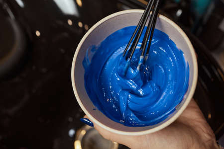 girl in white rubber protective gloves holding a brush in her hands and stirring hair dye close-up colorist.の写真素材