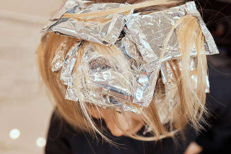 Hair stylist makes bouffant using comb on thin strands. Shatush technique for hair lightening.の写真素材
