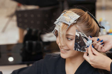 Hair stylist makes bouffant using comb on thin strands. Shatush technique for hair lightening.