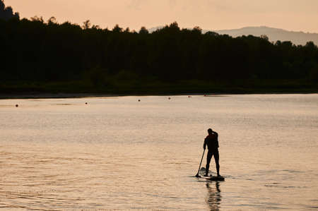 Active leisure in summer lifestyle. A boy rides on the sea in a sap. Concept of solitude, outdoor recreation, hygge.の写真素材