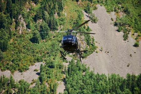 Altai Republic, Russia - 05 October, 2021: A blue helicopter in the mountains is landing. Skids are...