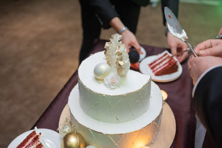 hands of bride and groom cut of a slice of a wedding cake.の写真素材
